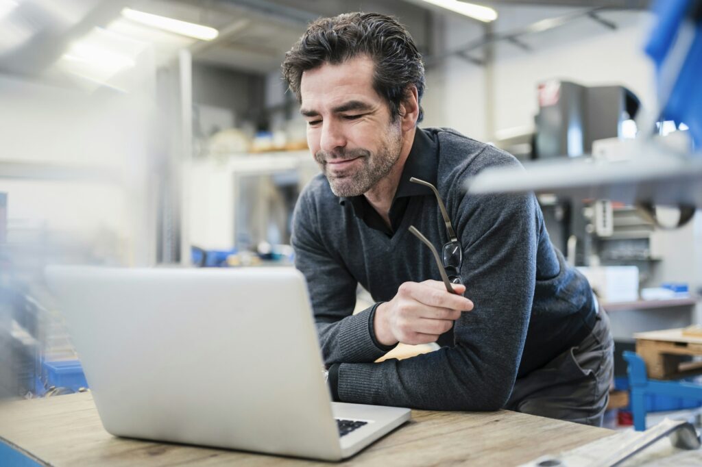 Businessman using laptop in a factory